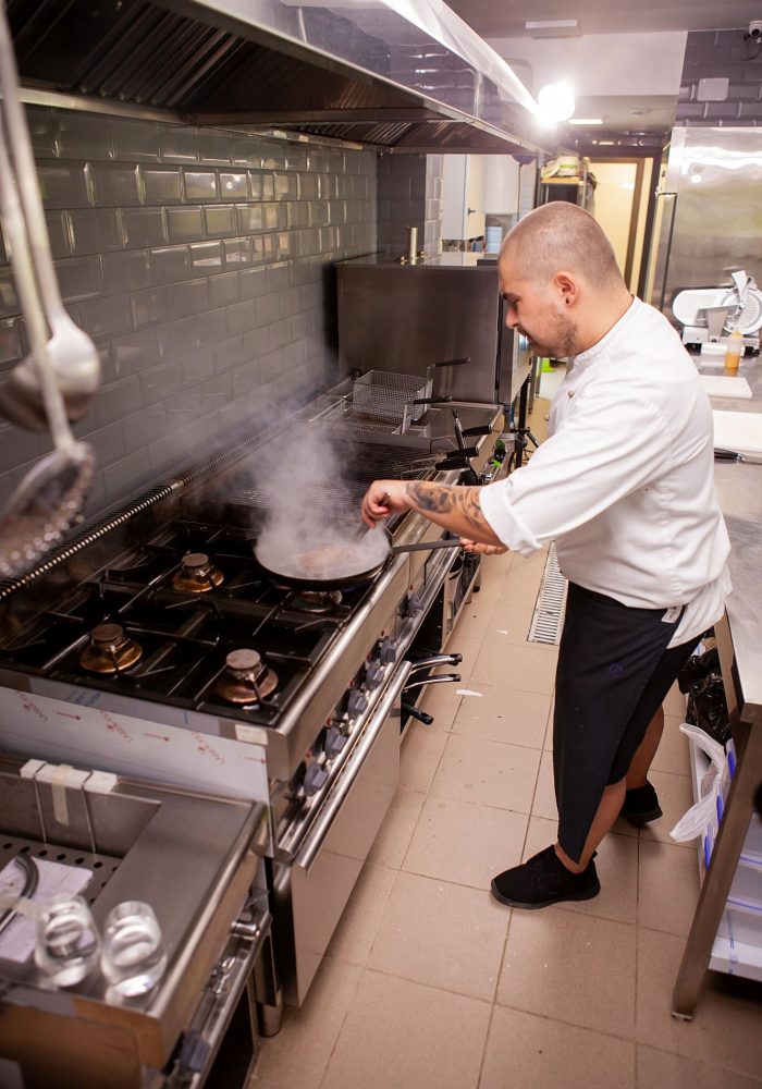 Chef cooking with flame on his restaurant kitchen.Skilled cook