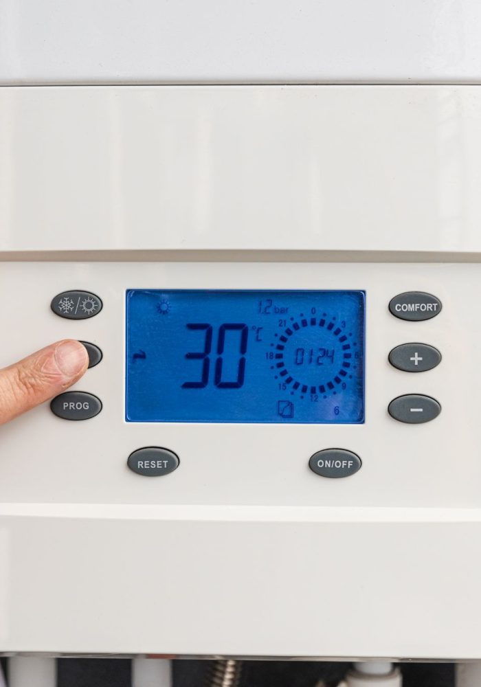 Hand adjust gas boiler control panel for comfort home heating and hot water. Concept of energy saving and heat conservation.
