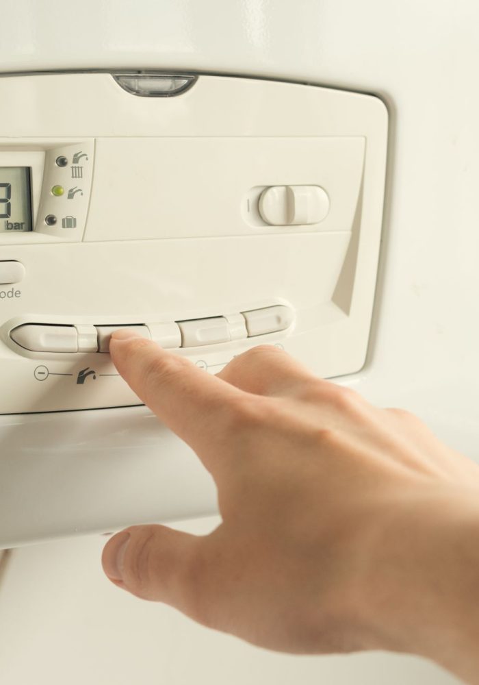 Man setting temperature on a heating boiler construction. Close up shot.